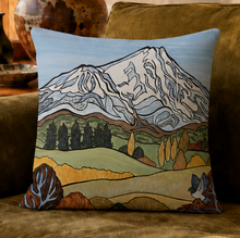 Load image into Gallery viewer, A square decorative throw pillow featuring a stylized landscape of Taranaki mountain, trees, rolling hills, and a wood pigeon, displayed on a brown upholstered sofa.